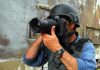 Person in helmet taking photos with a large camera.
