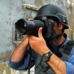 Person in helmet taking photos with a large camera.