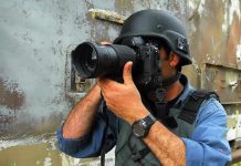 Person in helmet taking photos with a large camera.