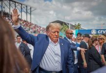 Person in blue suit waving at outdoor event.