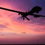 Silhouette of a drone against a colorful sunset.