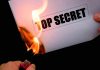 A hand holding a lighter igniting a paper labeled 'TOP SECRET' as it catches fire