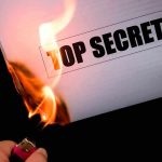 A hand holding a lighter igniting a paper labeled 'TOP SECRET' as it catches fire