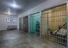 Interior view of a prison cell block with metal bars and concrete flooring