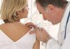 Doctor examining a patients skin with a magnifying glass