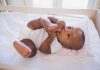 A playful baby lying in a crib, holding their feet