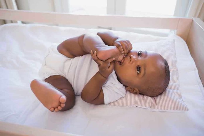 shutterstock_209676313.jpg A playful baby lying in a crib, holding their feet