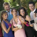 Group of friends in formal attire posing for a photo during prom night