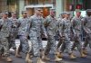 Group of soldiers marching in a military parade on a city street