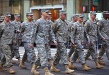 Group of soldiers marching in a military parade on a city street