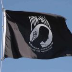 POW MIA flag waving against a blue sky