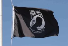 POW MIA flag waving against a blue sky