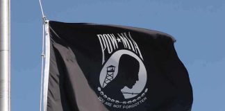 POW MIA flag waving against a blue sky