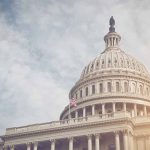 Trump Calls for Repeal of CHIPS and Science Act Capitol dome with American flag, under cloudy sky.