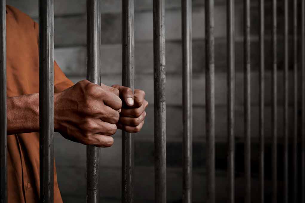772489252 featured image Person gripping metal jail bars tightly