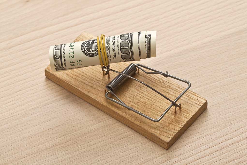 128877172 featured image Mousetrap baited with rolled dollar bills on table