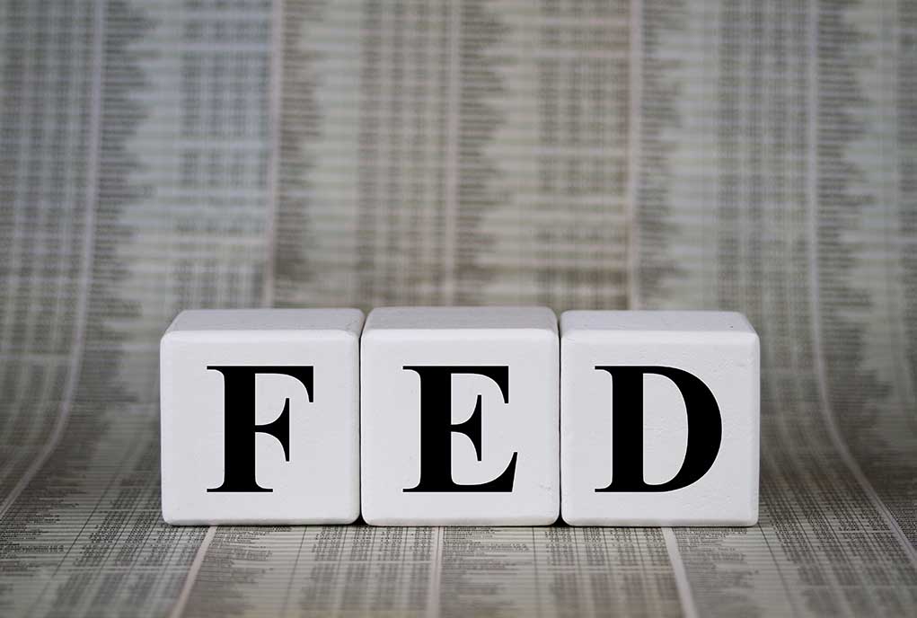 Blocks spelling FED against financial chart background.