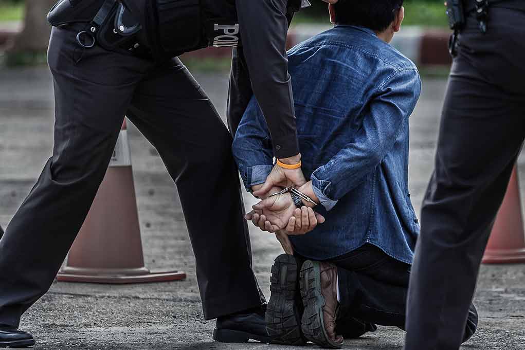 659470504 featured image Person kneeling with hands cuffed behind back