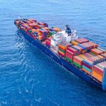 Cargo ship carrying colorful containers in open sea.