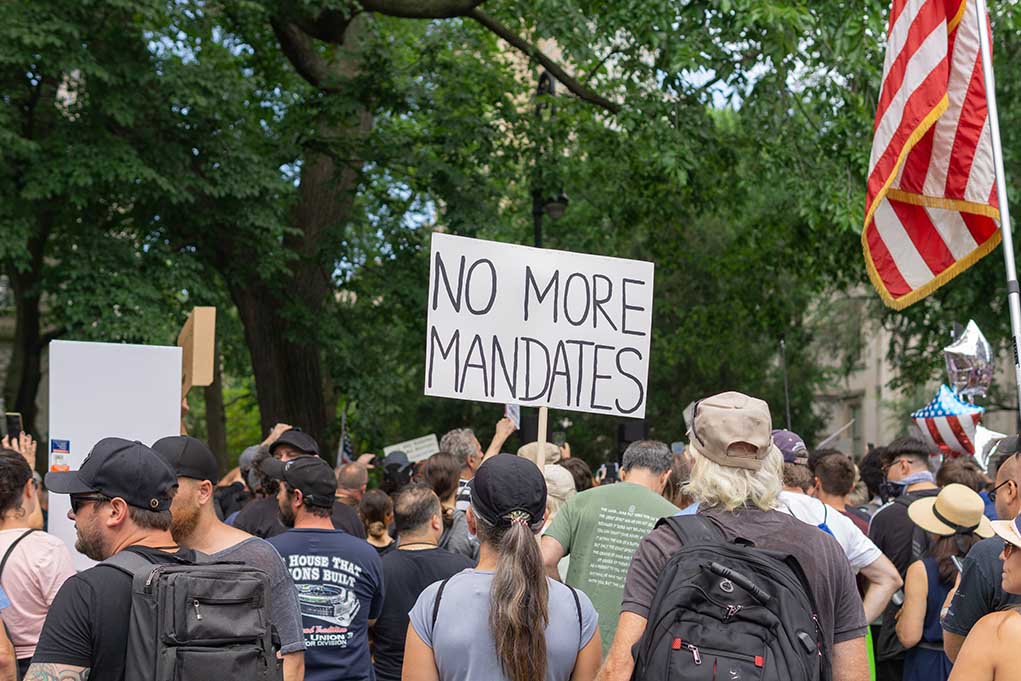 Crowd holds No More Mandates sign at protest