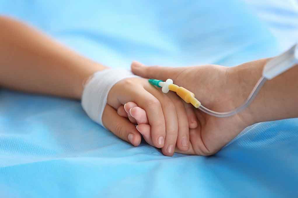 Two hands holding one with medical IV attached