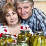 Older couple smiling with jars of pickles