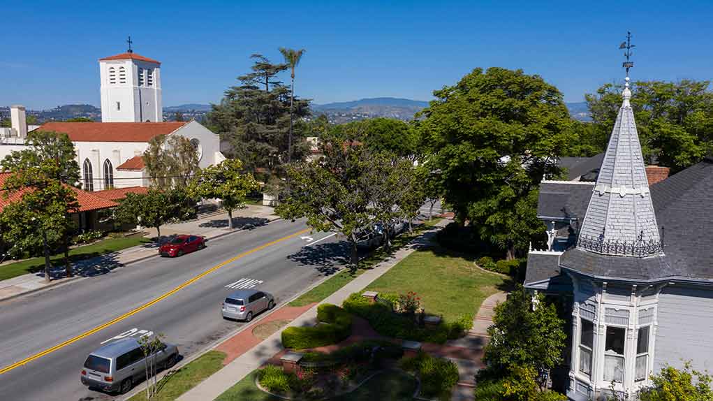 Street with church, parked cars, and trees