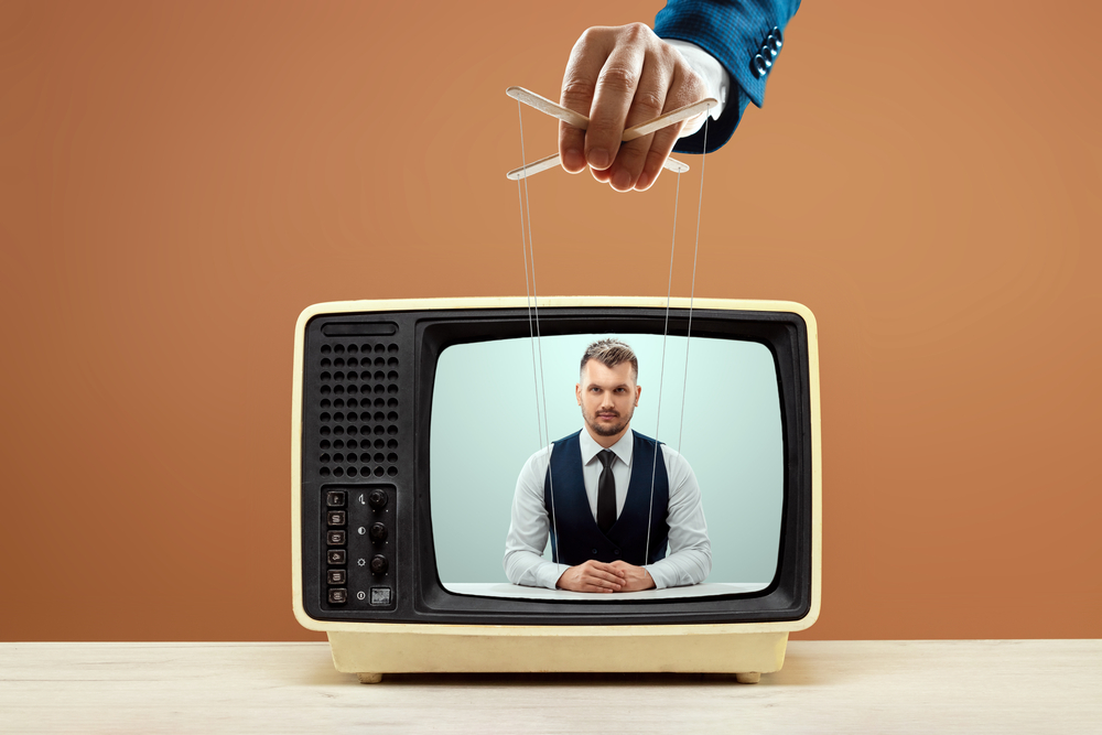 Hand controlling puppet strings on TV broadcast