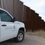 Border protection vehicle near a large metal fence