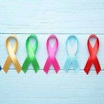 Colorful awareness ribbons on light wooden background