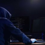 SHOCK FIND: Foreign Agents Masquerading as U.S. Workers Hooded figure using dual monitors in dark room