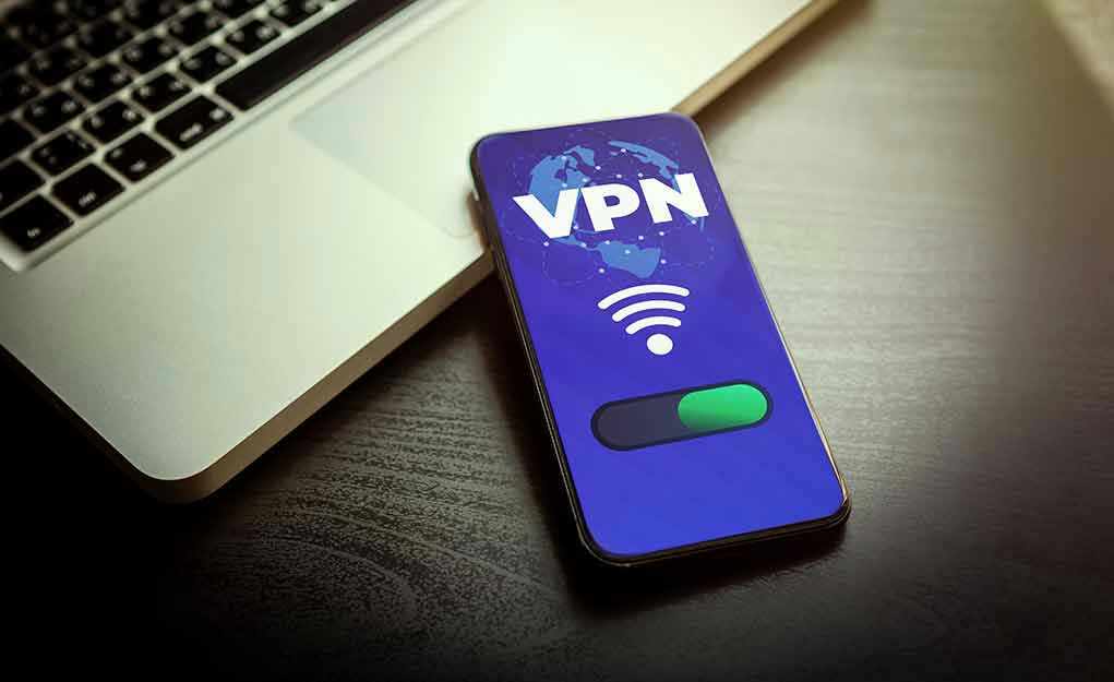 2033310410 Smartphone displaying VPN app beside a laptop