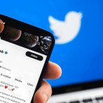 Hand holding phone displaying Twitter profile