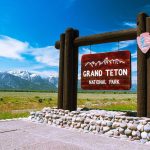 Entrance sign for Grand Teton National Park with mountains in the background