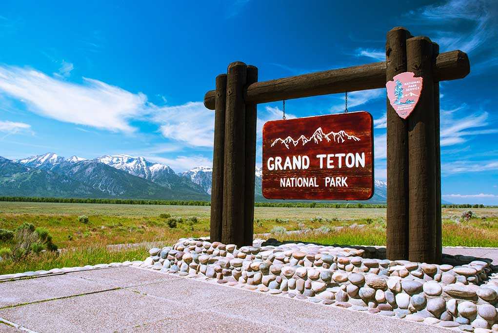Entrance sign for Grand Teton National Park with mountains in the background