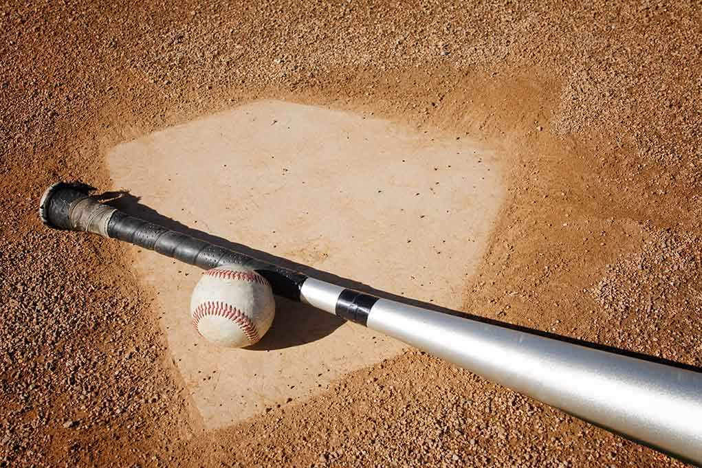 A baseball bat and ball resting on a baseball diamond