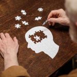Game-Changer: Lithium’s Unexpected Alzheimer’s Impact Elderly person completing head-shaped jigsaw puzzle.