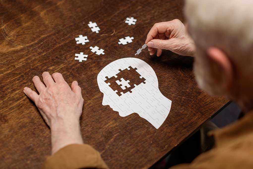 1776503864 Elderly person completing head-shaped jigsaw puzzle.
