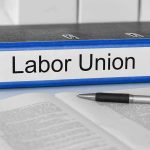 Blue binder labeled Labor Union beside papers and pen.