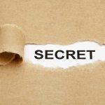City Official’s Hidden Past Sparks Outrage A torn piece of brown paper revealing the word SECRET underneath