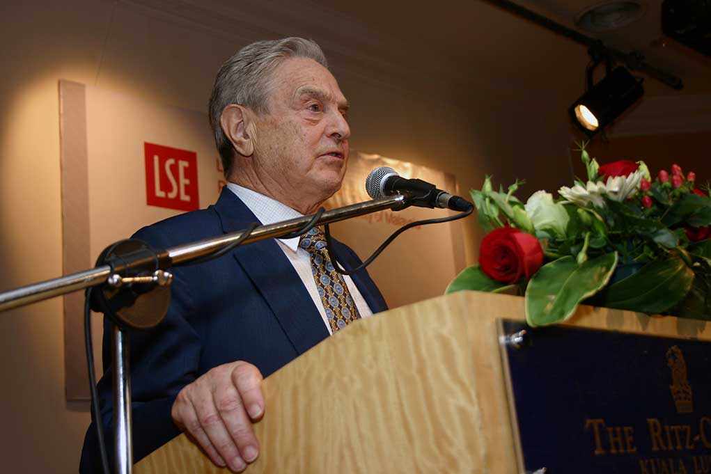 shutterstock_38657317.jpg A man in a suit speaking at a podium with flowers and a microphone