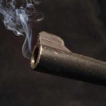 14-Year-Old’s Deadly Move Shocks Authorities Close-up of a gun barrel emitting smoke against a black background
