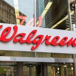 Walgreens store entrance sign with city reflections.
