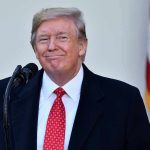 Trump’s $2B Plan Sparks CONSERVATIVE OUTRAGE Man in suit and tie speaking at podium.