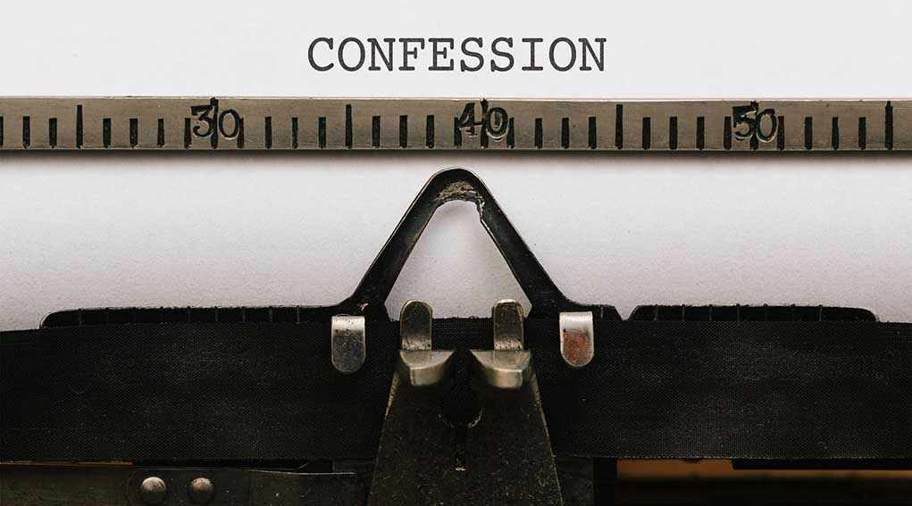 Typewriter typing the word confession on paper