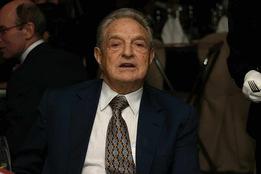 Elderly man in a suit sitting at a dining table during a formal event