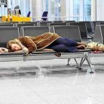 Major Airports PARALYZED: Thousands Left Stranded! A traveler sleeping on a bench in an airport waiting area