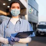 Nurse’s SHOCKING Double Life—Suburbia Duped! Nurse in scrubs and mask outside hospital holding clipboard.