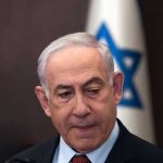 Netanyahu UNLEASHES Strikes – Obliterates GAZA! Man in suit with Israeli flag in background.