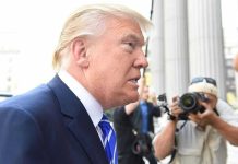 Trump CONCEDES – GOP Carnage Ensues! Man in suit with photographers in background.